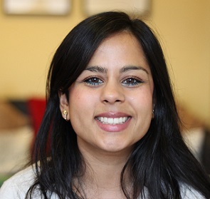 A photograph of Dr Sheila Kanani smiling at the camera with a blurred room in the background